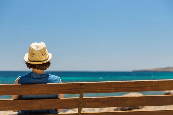 Fiatal nő egyedül ül egy padon a tengerparton — Stock Fotó