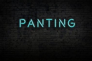 Neon işareti. Kelimeler tuğla duvara karşı soluk soluğa. Gece görünümü