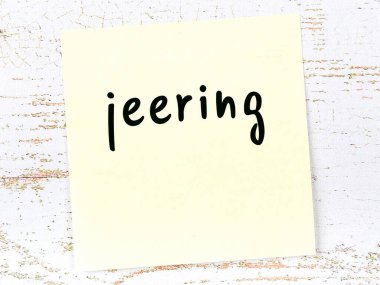 Tahta duvardaki sarı yapışkan nota, el yazısıyla yazılmış alay ediyor.