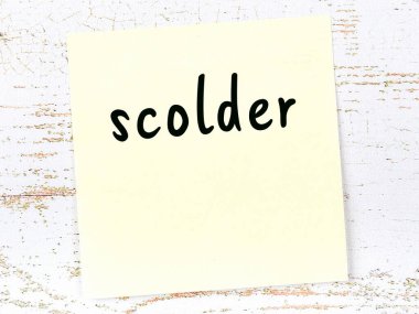 Tahta duvarda el yazısıyla yazılmış sarı yapışkan bir not.