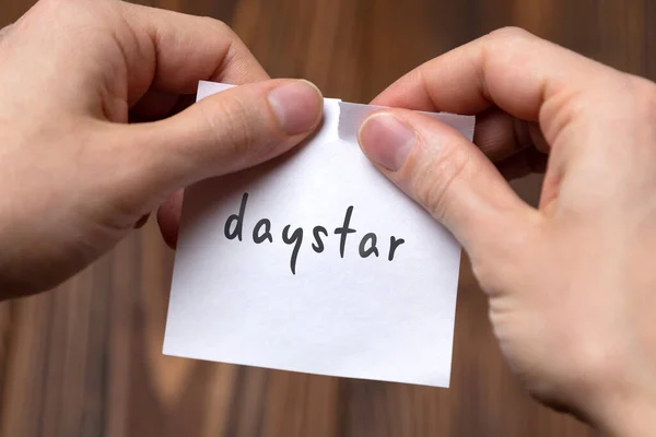 Mãos de um homem rasgando um pedaço de papel com inscrição daystar — Fotografia de Stock