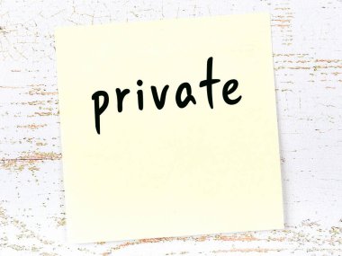 Tahta duvardaki sarı yapışkan notta el yazısıyla yazılmış özel kelimeler var.