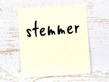 Tahta duvarda el yazısıyla yazılmış sarı yapışkan bir not var.