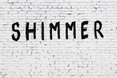 Beyaz tuğla duvara yazıtlar çizilmiş.