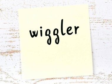 Tahta duvardaki sarı yapışkan nota, el yazısıyla yazılmış kelime oynatıcı.