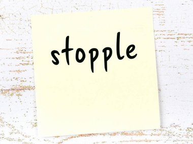 Tahta duvarda el yazısıyla yazılmış sarı yapışkan bir not var.