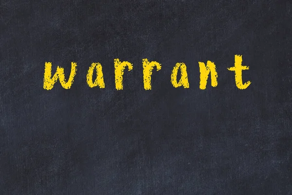 College chalk desk with the word warrant written on in — Stock Photo, Image
