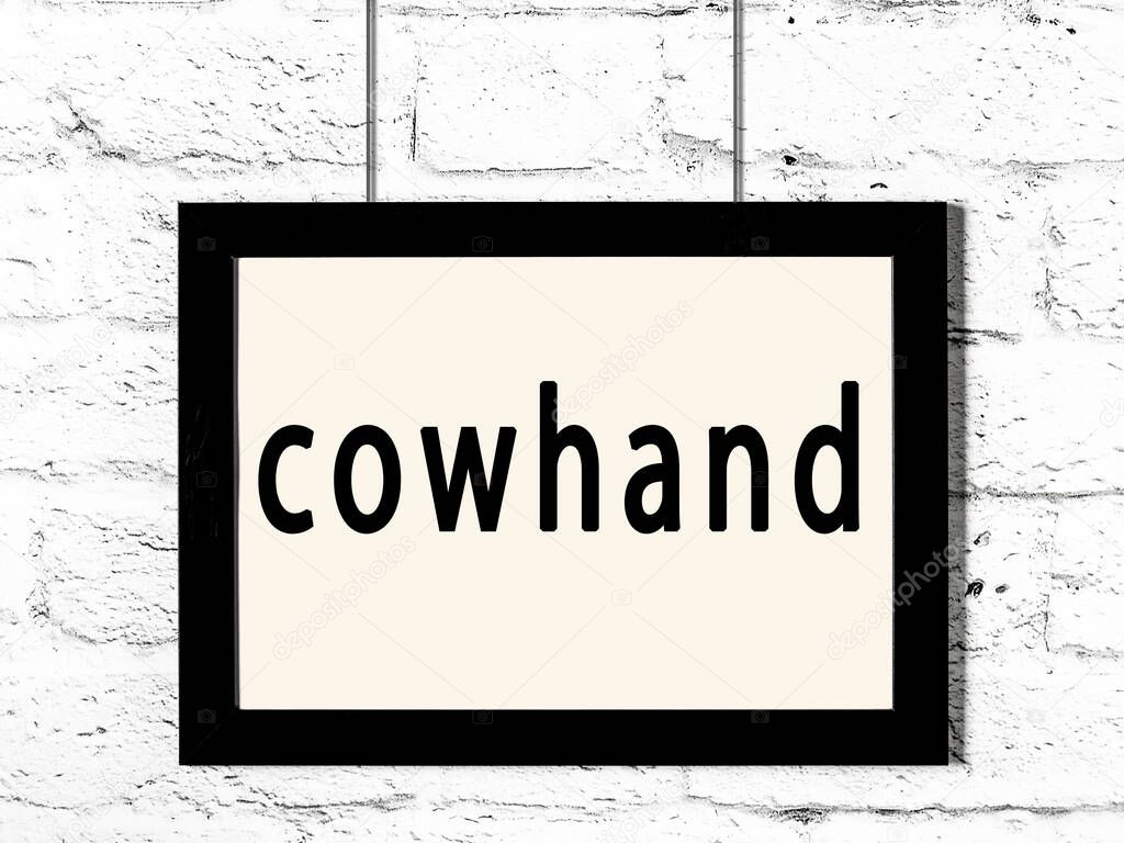 Black frame hanging on white brick wall with inscription cowhand