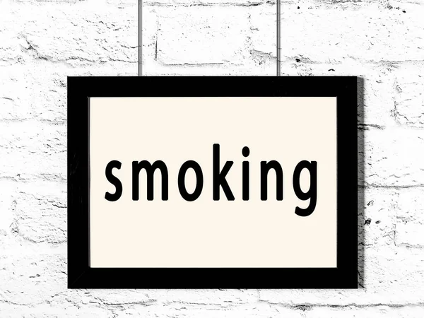 Marco negro colgando en la pared de ladrillo blanco con inscripción fumar —  Fotos de Stock