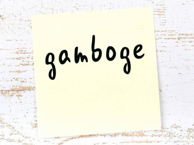 Tahta duvarda el yazısıyla yazılmış sarı yapışkan bir not var.