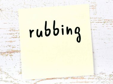 Tahta duvarda el yazısıyla yazılmış sarı yapışkan bir not var.