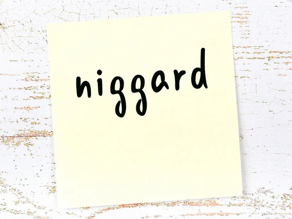 Nota adesiva gialla su parete di legno con parola scritta a mano niggard — Foto Stock