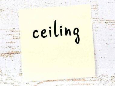 Tahta duvarda el yazısıyla yazılmış sarı yapışkan bir not var.