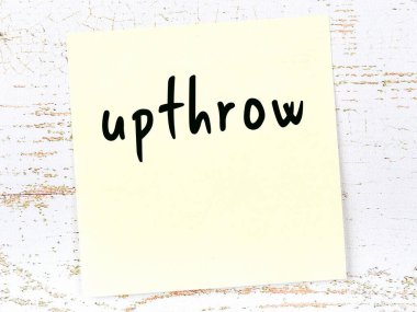 Tahta duvarda el yazısıyla yazılmış sarı yapışkan bir not var.