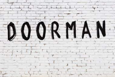 Beyaz tuğla duvara yazı yazan kapıcı.