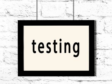 Beyaz tuğla duvarda asılı siyah çerçeve yazı testi ile