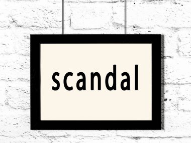Beyaz tuğla duvarda asılı siyah çerçeve ve yazı skandalı