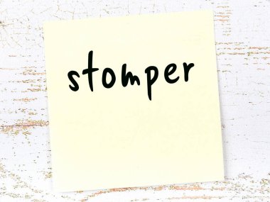 Tahta duvarda el yazısıyla ezilmiş sarı yapışkan bir not.