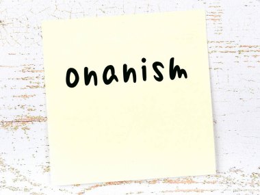 Tahta duvarda el yazısı onanizm olan sarı yapışkan bir not.