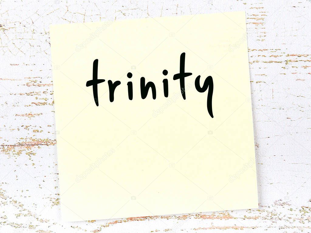 Yellow sheet of paper with word trinity. Reminder concept