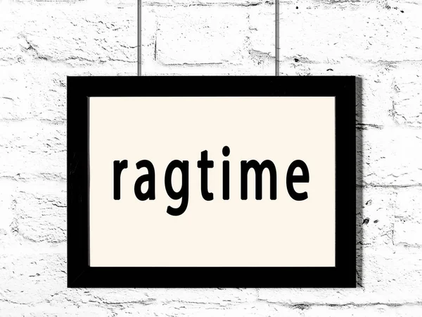 Черная рамка висит на стене из белого кирпича с надписью ragtime — стоковое фото