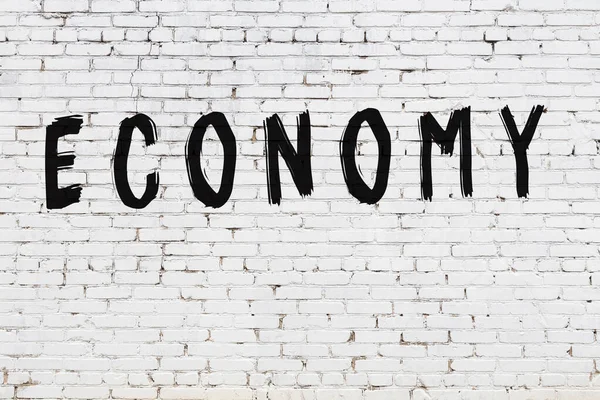 Inscription ekonomika malované na bílou cihlovou zeď — Stock fotografie