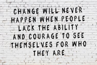 Beyaz tuğla duvara zekice alıntılar yazılı siyah bir yazı.