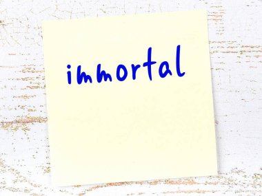 Ölümsüzlüğü hatırlatma kavramı. Tahta duvarda üzerinde yazı olan sarı yapışkan kağıt.