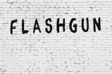 Üzerinde siyah boya yazılı el feneri olan beyaz tuğla bir duvar.