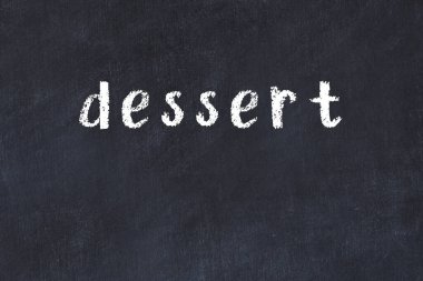 Tebeşir el yazısıyla yazılmış tatlı, siyah masanın üstünde.