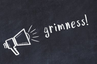 Hoparlörün tebeşir çizimi ve siyah masanın üzerine el yazısıyla yazılmış grimlik.