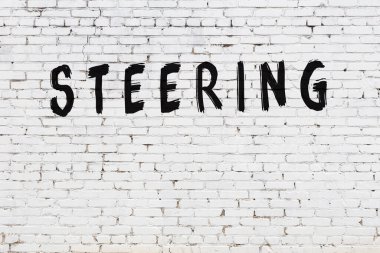 Yazı direksiyonu beyaz duvara siyah boya ile yazılmış..