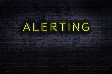 Tuğla duvara karşı uyarısı olan neon tabela. Gece görünümü
