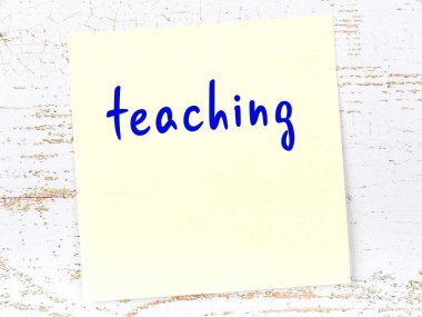 Öğretmenlik hakkında hatırlatma kavramı. Tahta duvarda üzerinde yazı olan sarı yapışkan kağıt.