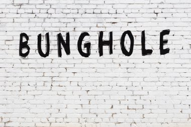 Beyaz tuğla duvarda siyah boyayla yazılmış bir kalça deliği..