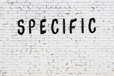 Beyaz tuğlalı duvar. Üzerinde siyah boya ile özel bir yazı var.