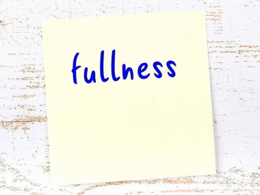 Tahta duvarda el yazısı dolu sarı yapışkan bir not var.