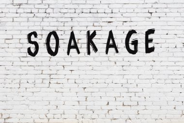 Beyaz tuğladan duvar ve siyah boyayla yazılan el yazısı.