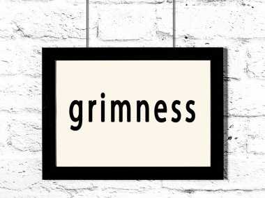 Siyah ahşap çerçeve, beyaz tuğla duvarda yazıtlar asılı. 