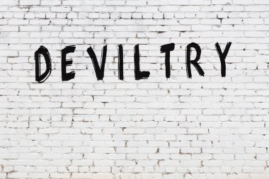 Beyaz tuğla duvara siyah boya ile yazılmış bir yazıt..