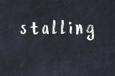 Tebeşir el yazısıyla yazılmış yazı, siyah masanın üzerinde duruyor.