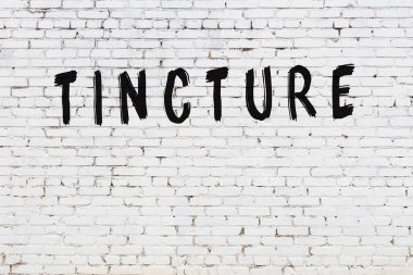 Beyaz tuğlalı duvar, siyah boyayla el yazısıyla yazılmış.