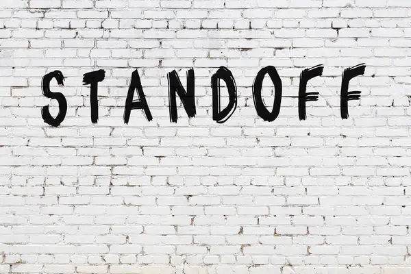 Yazılı beyaz tuğla duvar. Siyah boyayla yazılmış.