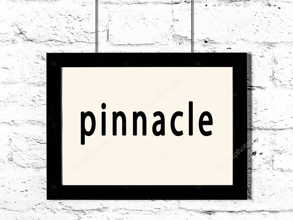 Black wooden frame with inscription pinnacle hanging on white brick wall 