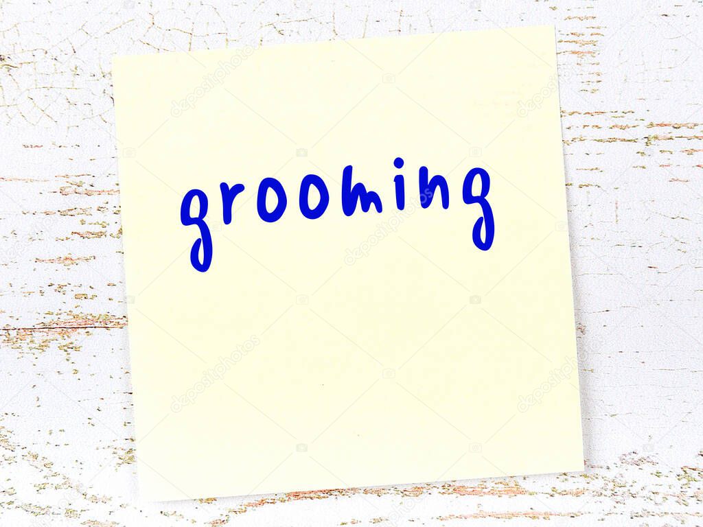 Concept of reminder about grooming. Yellow sticky sheet of paper on wooden wall with inscription