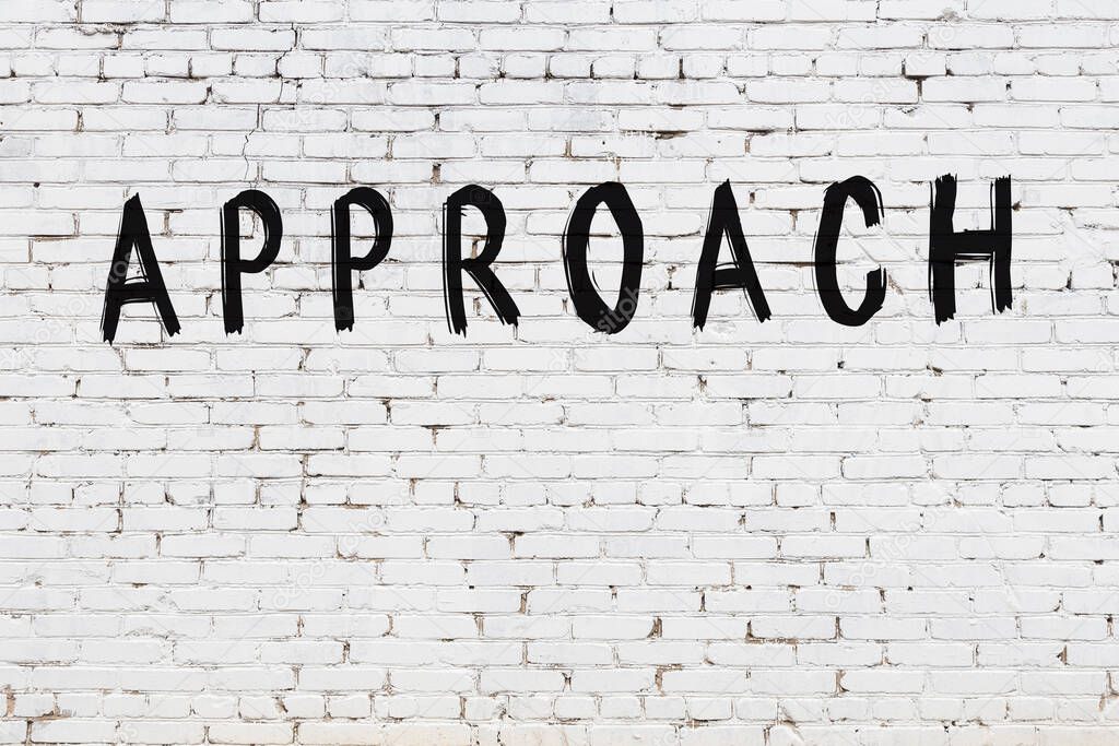 Inscription approach written with black paint on white brick wall.