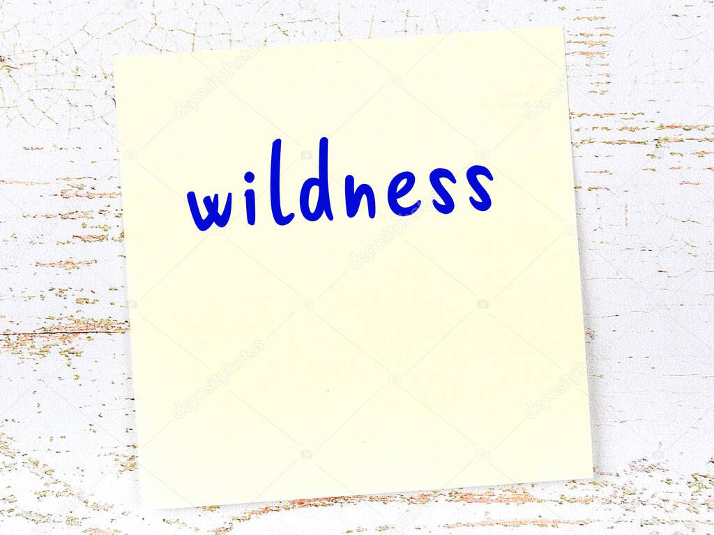 Concept of reminder about wildness. Yellow sticky sheet of paper on wooden wall with inscription