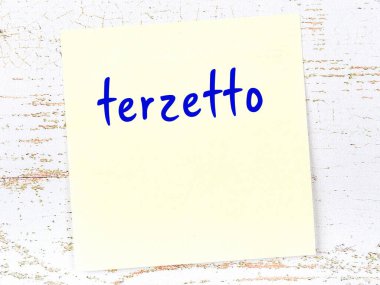 Tahta duvarda el yazısıyla yazılmış sarı yapışkan bir not var.