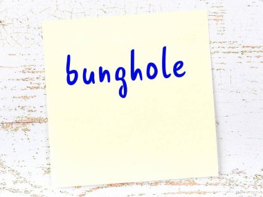 Tahta duvarda el yazısıyla yazılmış bir kalça deliği olan sarı yapışkan bir not.