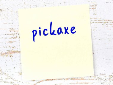 Tahta duvarda, el yazısıyla kazmalı sarı yapışkan bir not.